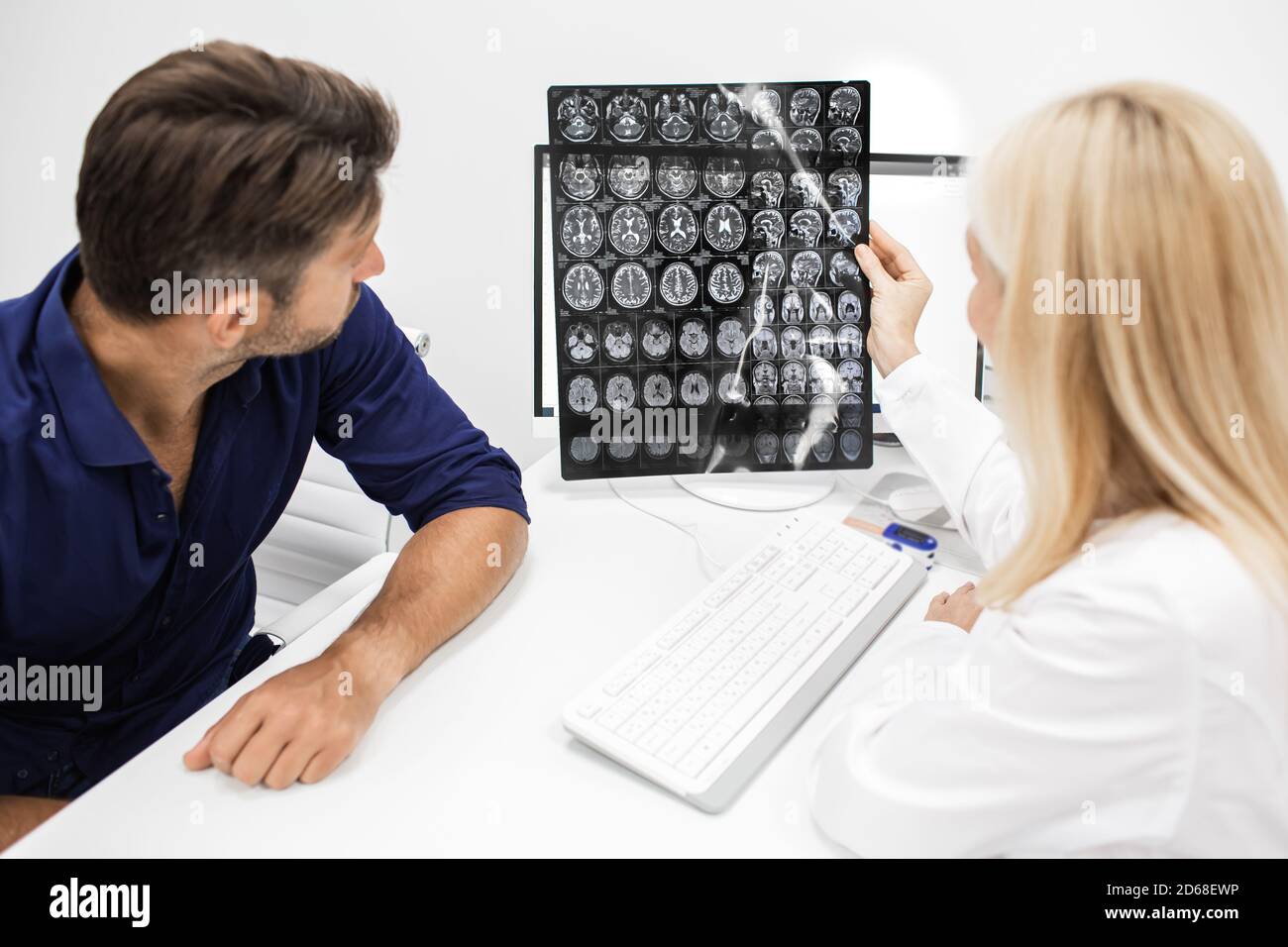 doctor explains to man patient the results of an MRI scan of his brain. Diagnosis of diseases and head injuries. Headache treatment Stock Photo