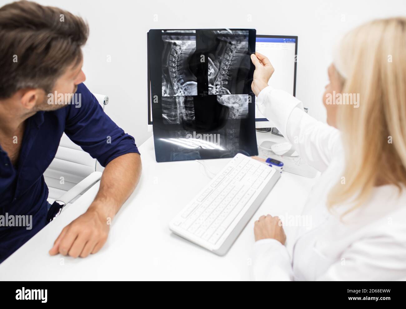 Neurologist considers and discusses with man patient an X-ray image of his cervical spine. Diagnostics and treatment of cervical osteochondrosis of sp Stock Photo