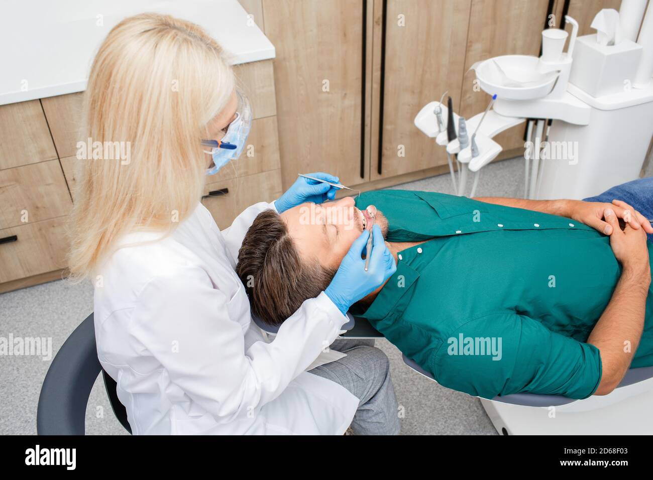 Adult female dentist exam teeth to a handsome man patient at dental clinic. Stomatology and health care concept Stock Photo