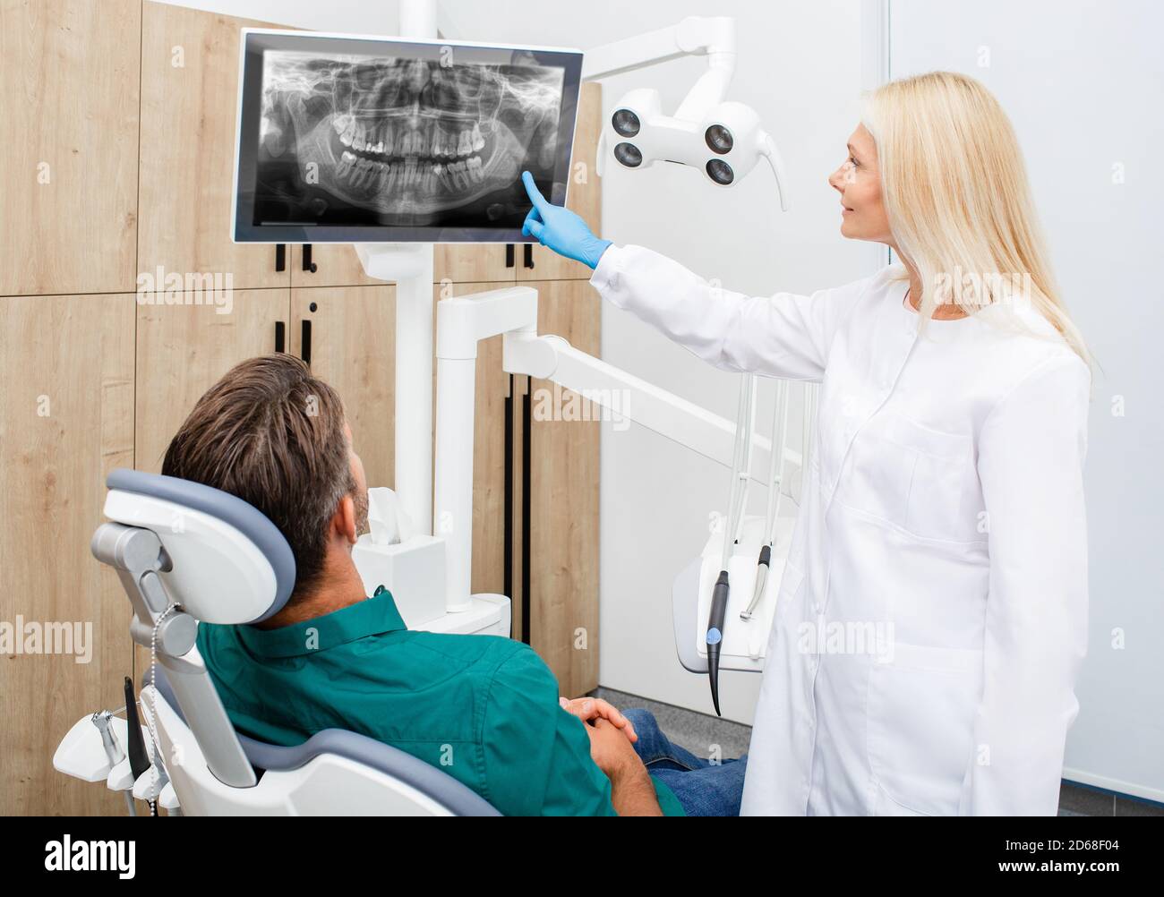 Beautiful woman dentist consulting a man patient, patient has a wisdom tooth ache. Treatment or extraction of a human wisdom tooth Stock Photo