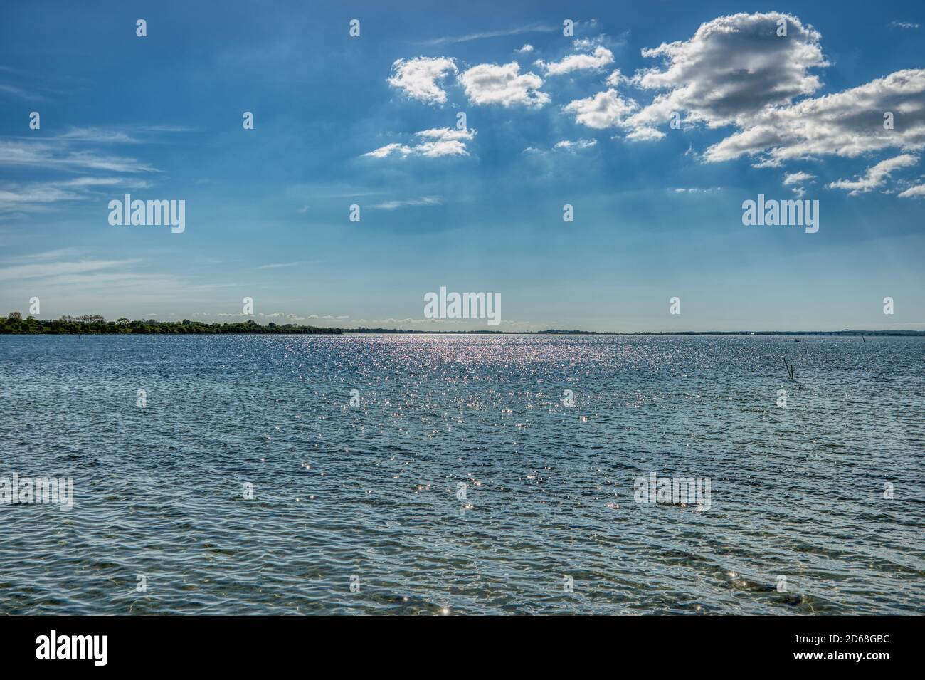 Blue sky with sun rays peeping through the clouds reflect on a calm Baltic Sea convey eternal freedom and motivational concept with sublime ecstatic Stock Photo