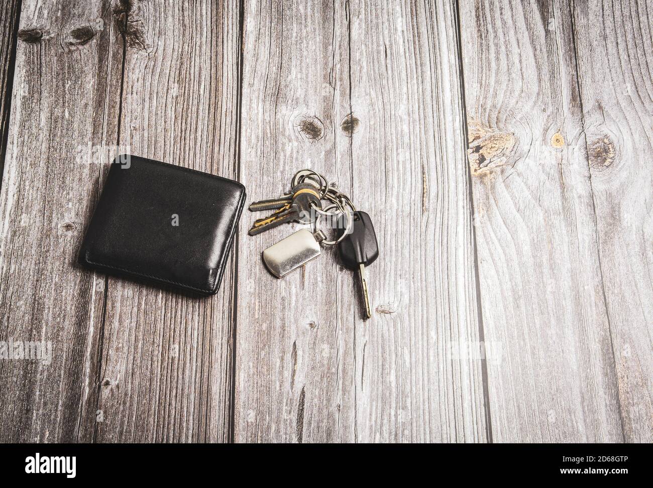 A wallet and a set of keys laid on a rustic wooden table or desk Stock Photo