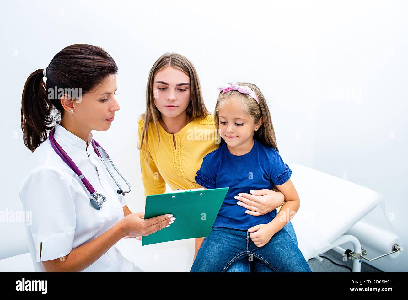 Smiling female consult parent with a cute child, make notes in patient care at medical checkup appointment. Stock Photo