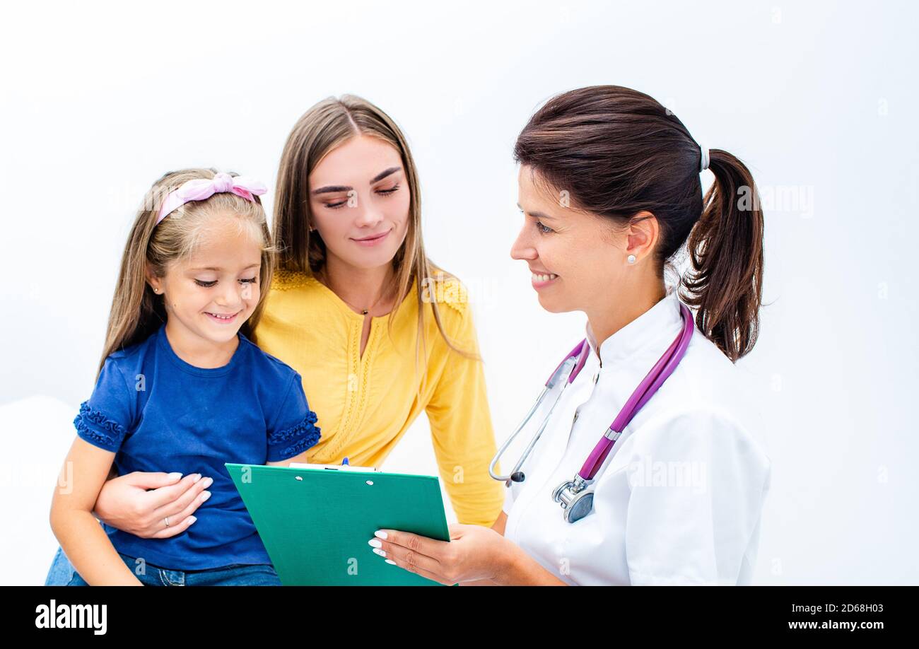 Smiling female consult parent with a cute child, make notes in patient care at medical checkup appointment. Stock Photo