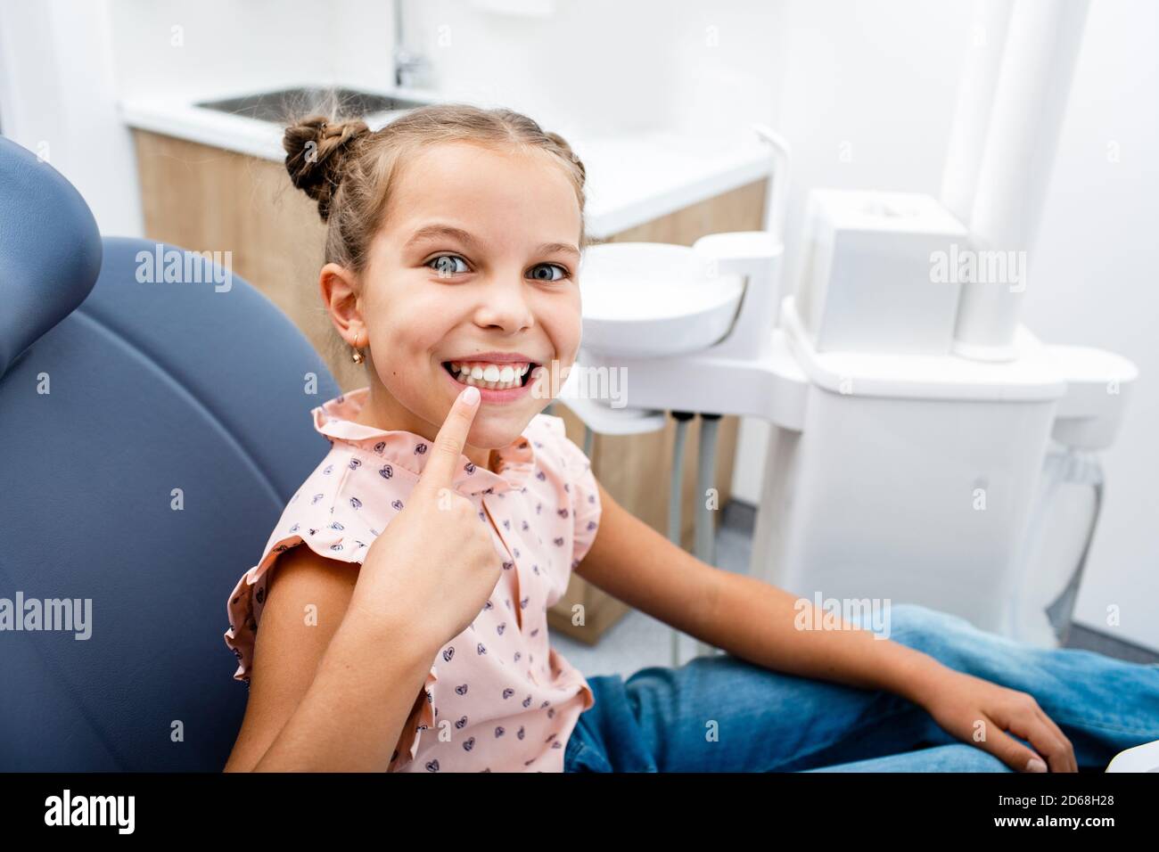 Emotional little girl pointing to a perfect healthy smile after tooth