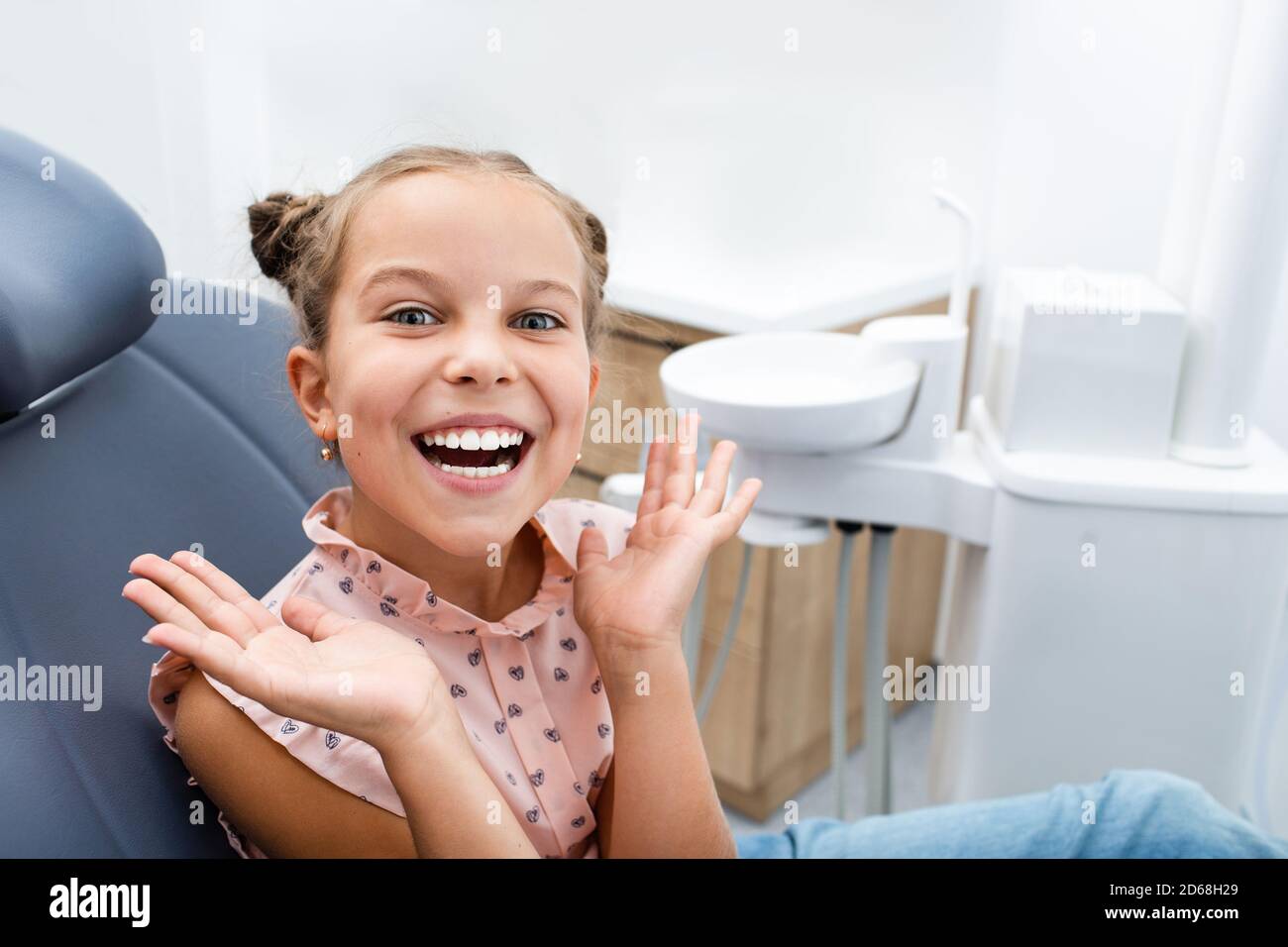 Very happy emotional child sitting on a dental chair and showing perfect healthy white smiling. Kid teeth treatment Stock Photo