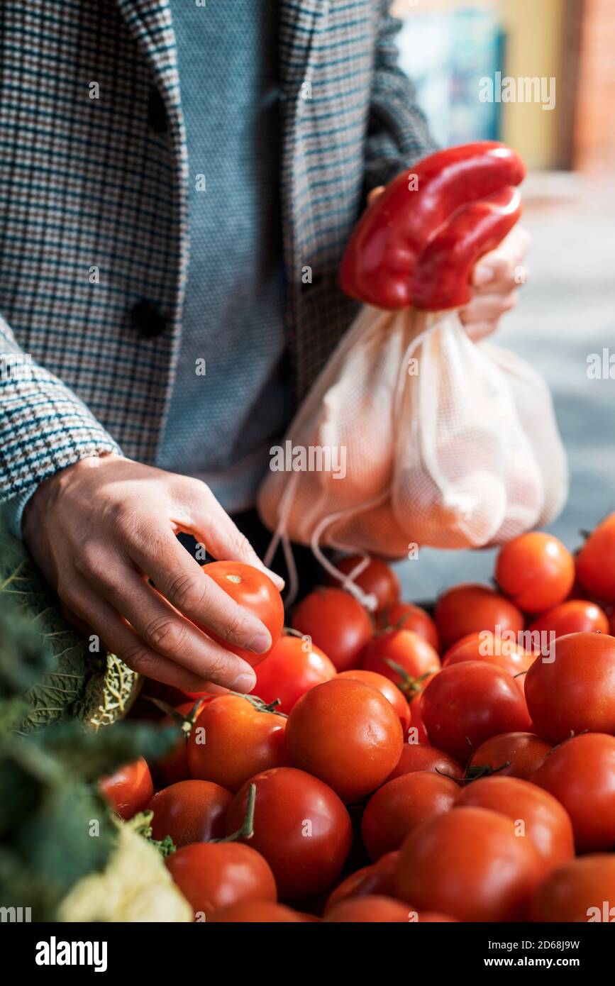 closeup of a man using textile reusable mesh bags while is shopping at a greengrocer or a street market as a measure to reduce plastic pollution Stock Photo