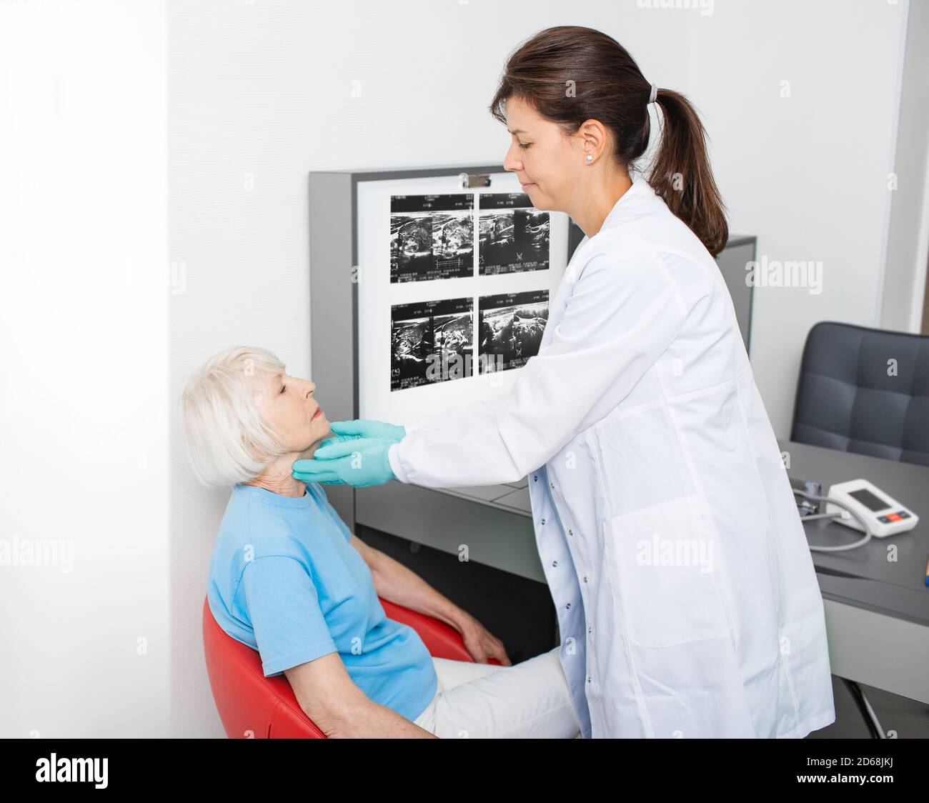 doctor checking the thyroid gland of an elderly woman. Diagnosis of thyroid diseases. Endocrine system treatment Stock Photo