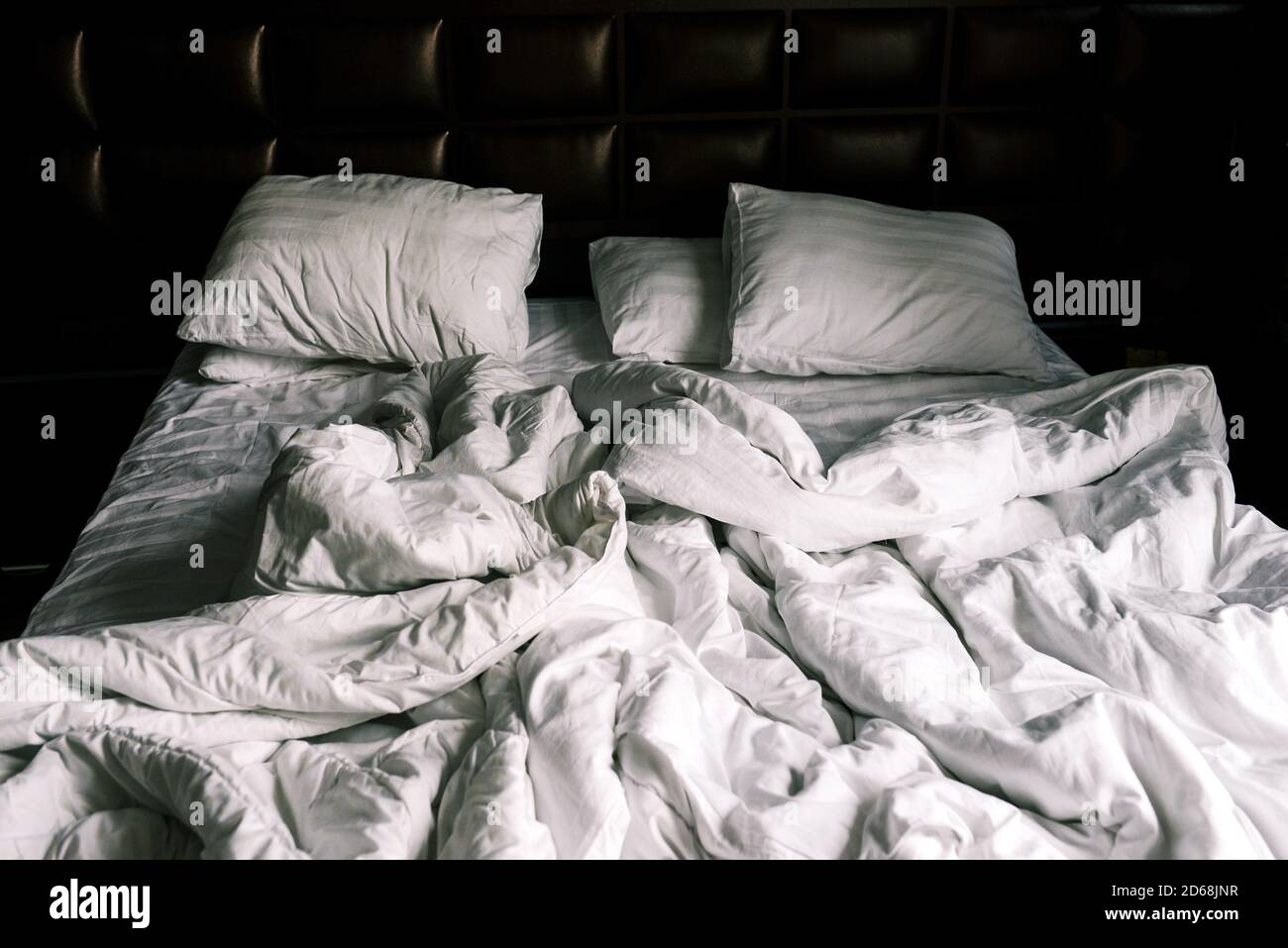Unmade double empty bed with white linens. Sheets and pillows in the apartment or hotel after a