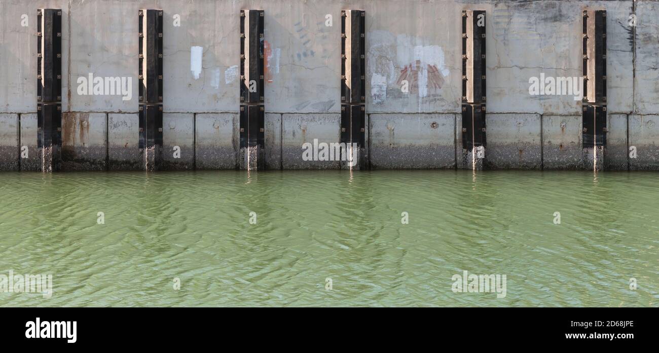 Concrete mooring wall with vertical dampers and sea water. Industrial transportation photo texture Stock Photo