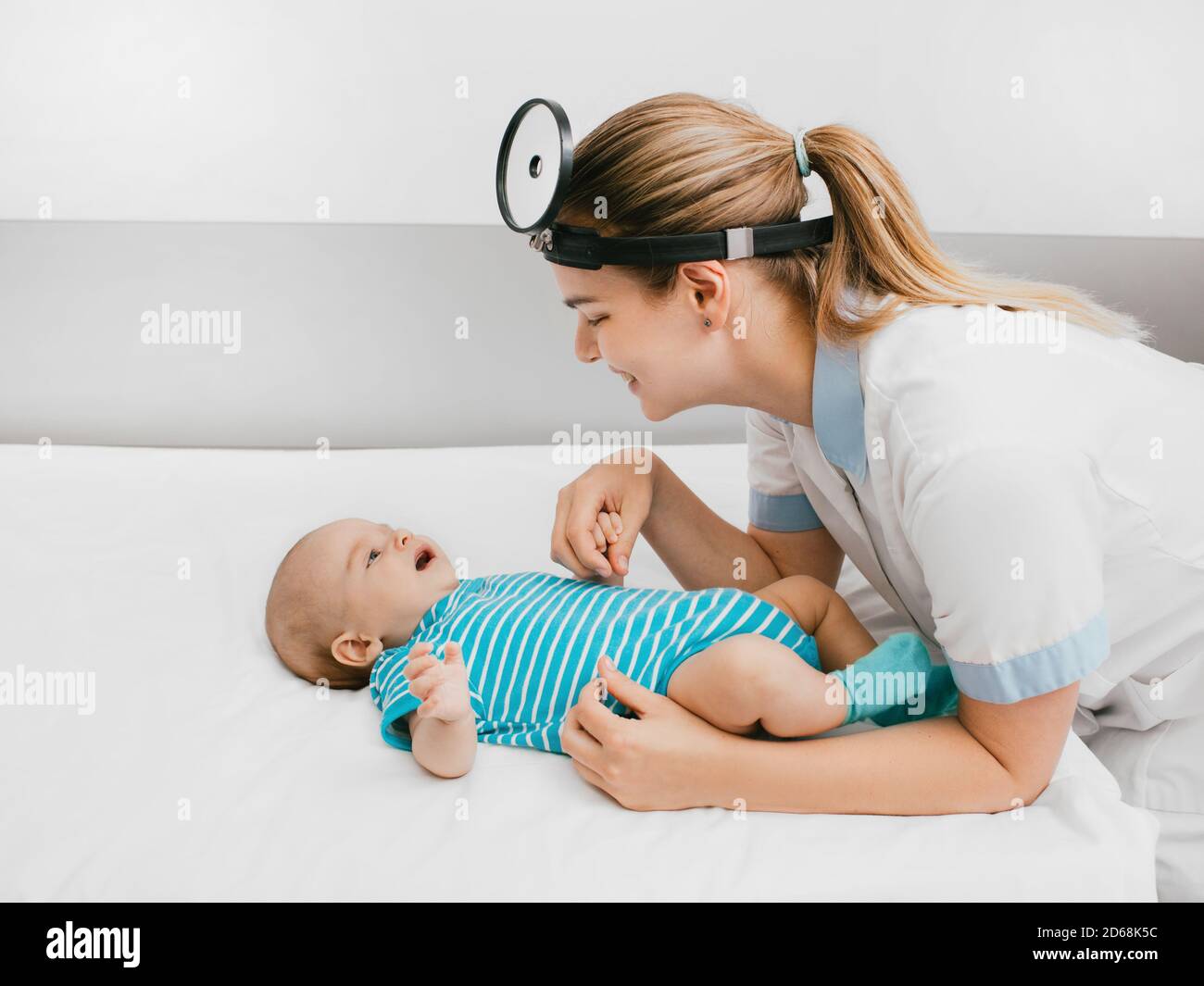 Smiling pediatrician communicate and playing with baby at the hospital. doctor examines infant baby 3-month-old Stock Photo