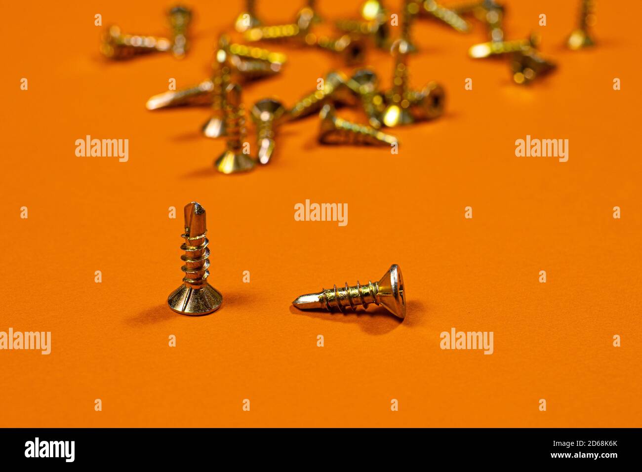 Self-cutters on a orange background. Furniture and parts for repair and construction. Self-tapping scew Stock Photo