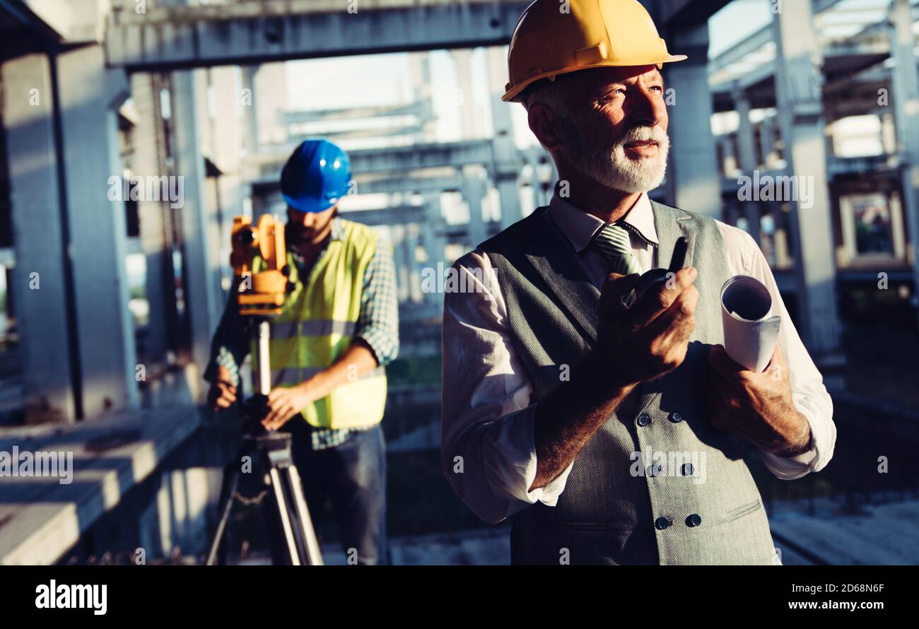 Two satisfied engineers talking at building site with construction structure in background Stock Photo