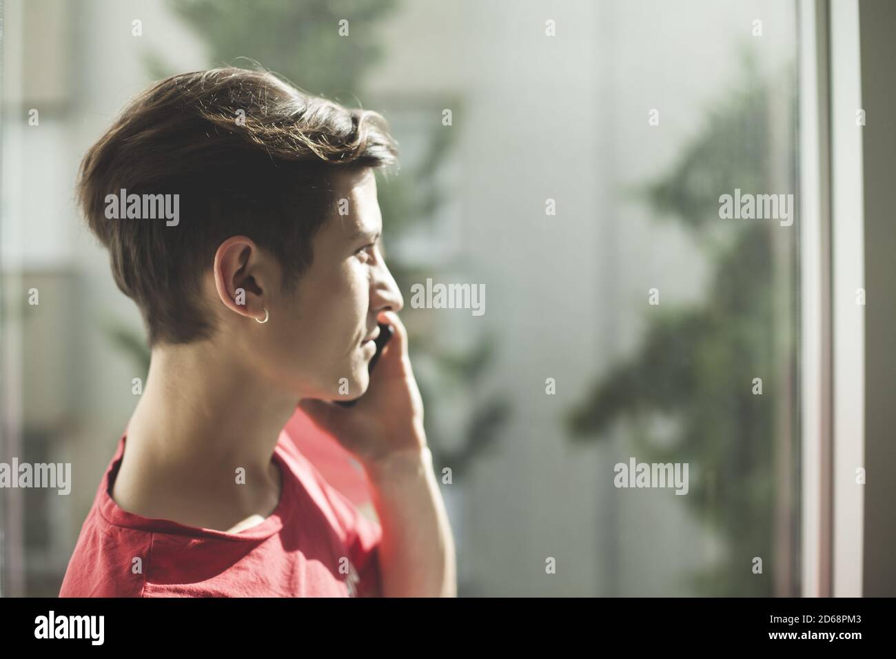 Young guy talking on phone by the window Stock Photo