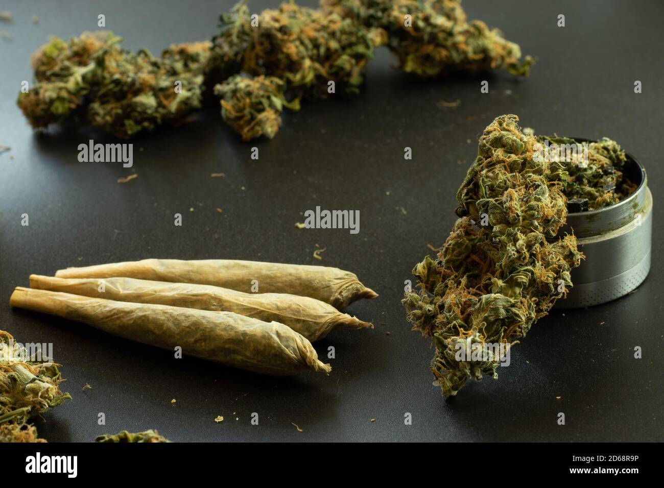 Weed joints on black background with marijuana buds and grinder closeup. Legal THC drug use in