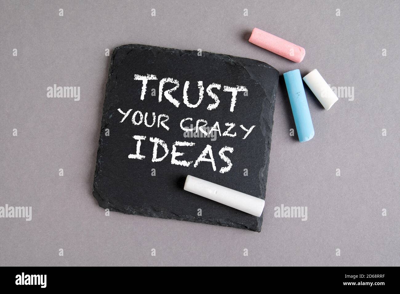TRUST YOUR CRAZY IDEAS. Text on a stone surface. Chalk on a gray background Stock Photo