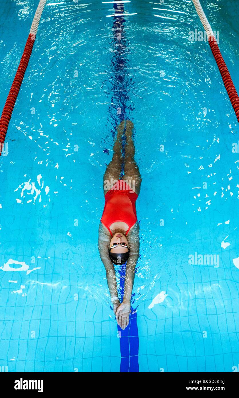 Woman swimmer swims backstroke in the pool. Top view, backstroke