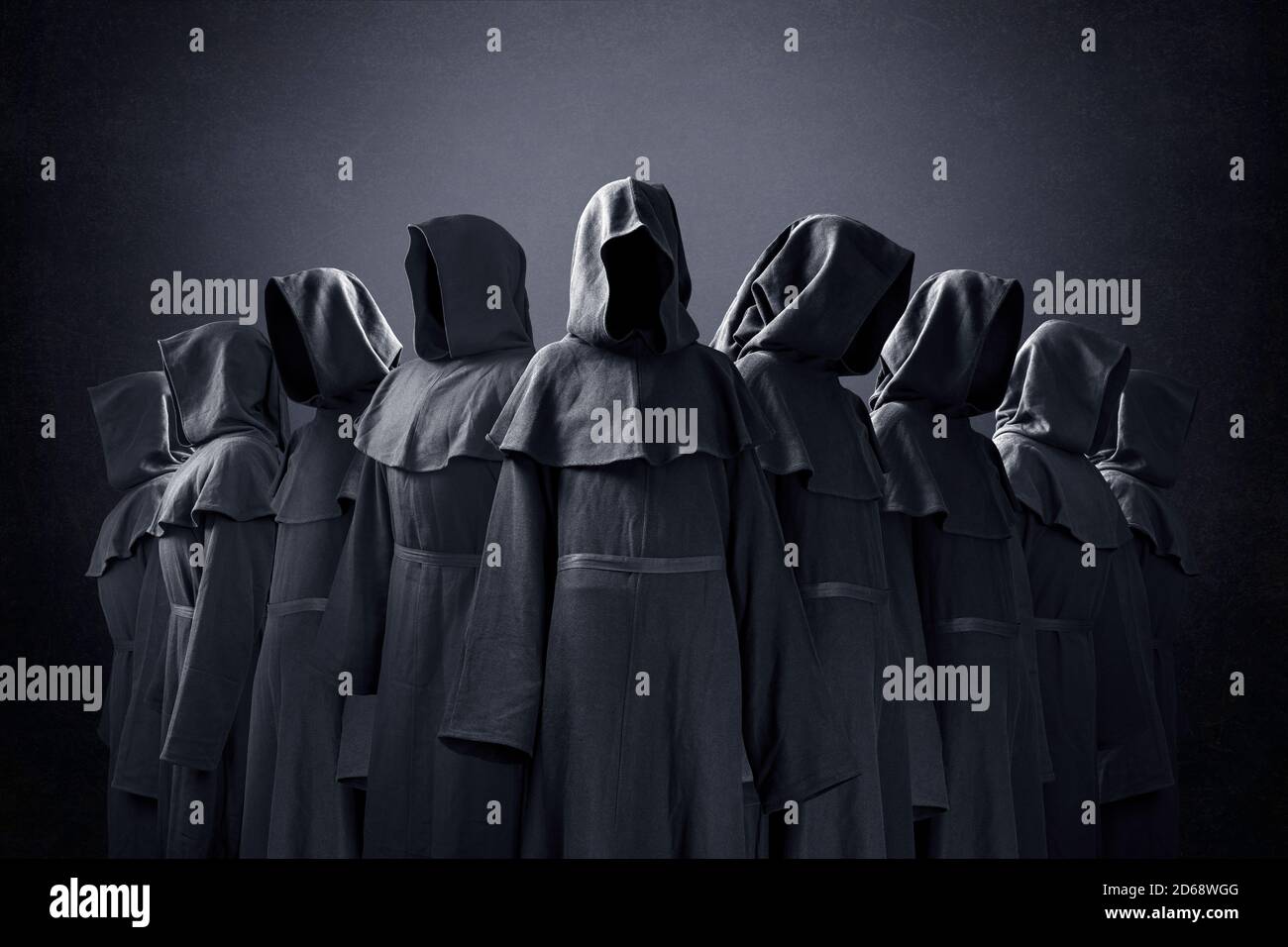 Group of nine scary figures in hooded cloaks in the dark Stock Photo