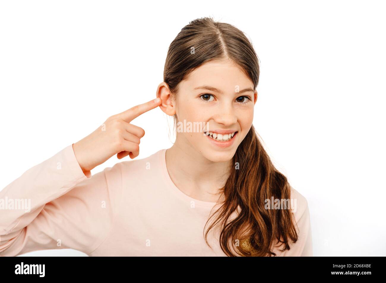 Pretty girl point on her ear and smiling. My hearing is perfect. Child hearing exam and hearing treatment concept Stock Photo