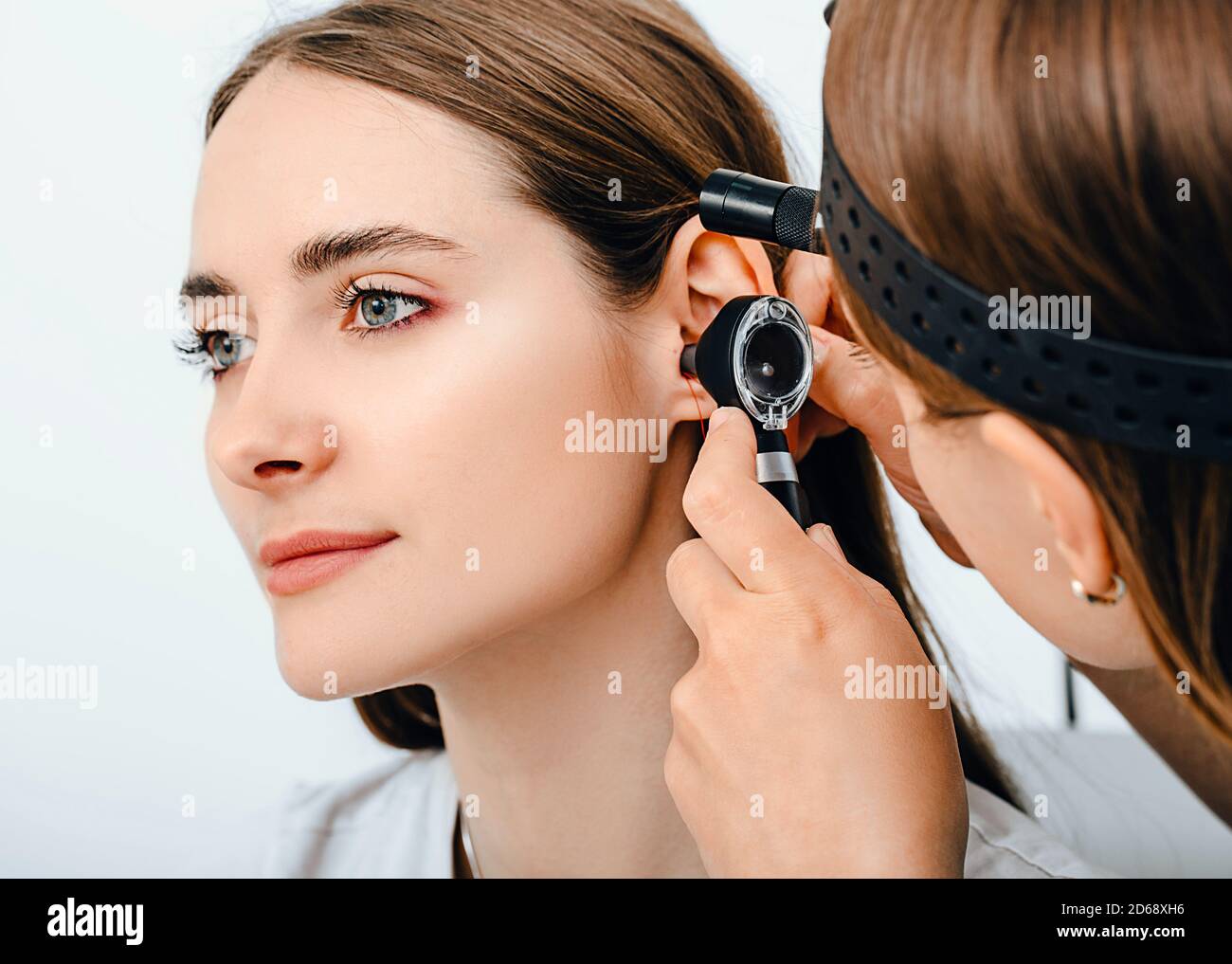 Audiologist doctor doing an ear exam with an otoscope to a patient
