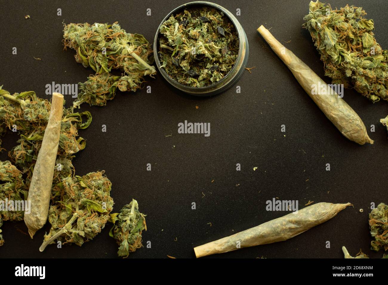 Rolled weed joint top view with cannabis buds on black background with copy space, grinder with marijuana. THC or CBD Design template Stock Photo