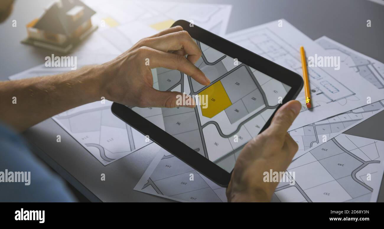 man searching building plot to buy on cadastral plan for house construction on digital tablet Stock Photo