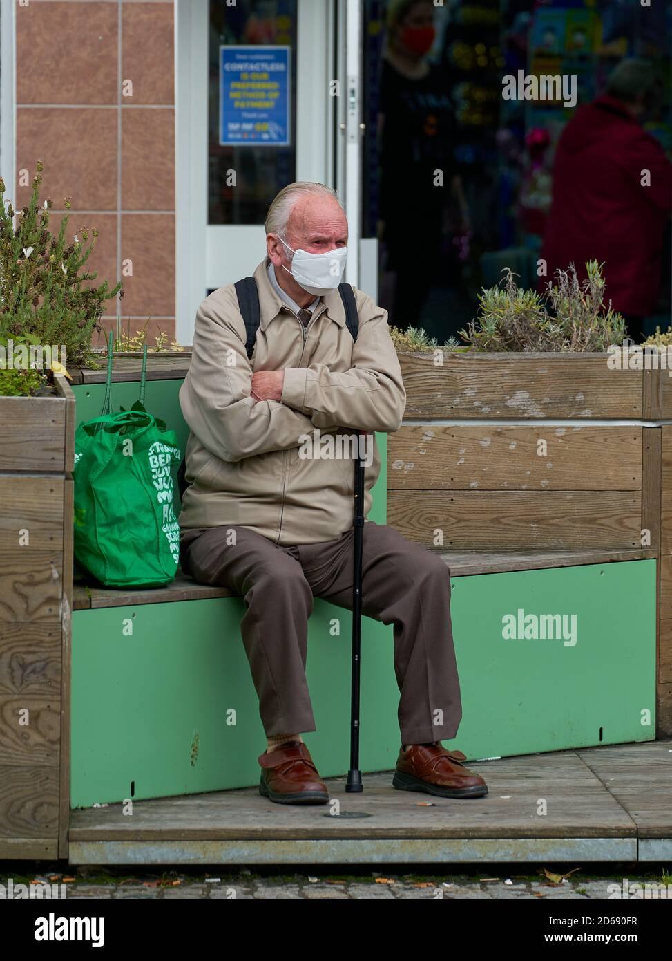 14 October 2020. High Street, Elgin, Moray, Scotland, UK. This is an elderly male sitting at the plainstones area, masked and walking stick. Stock Photo