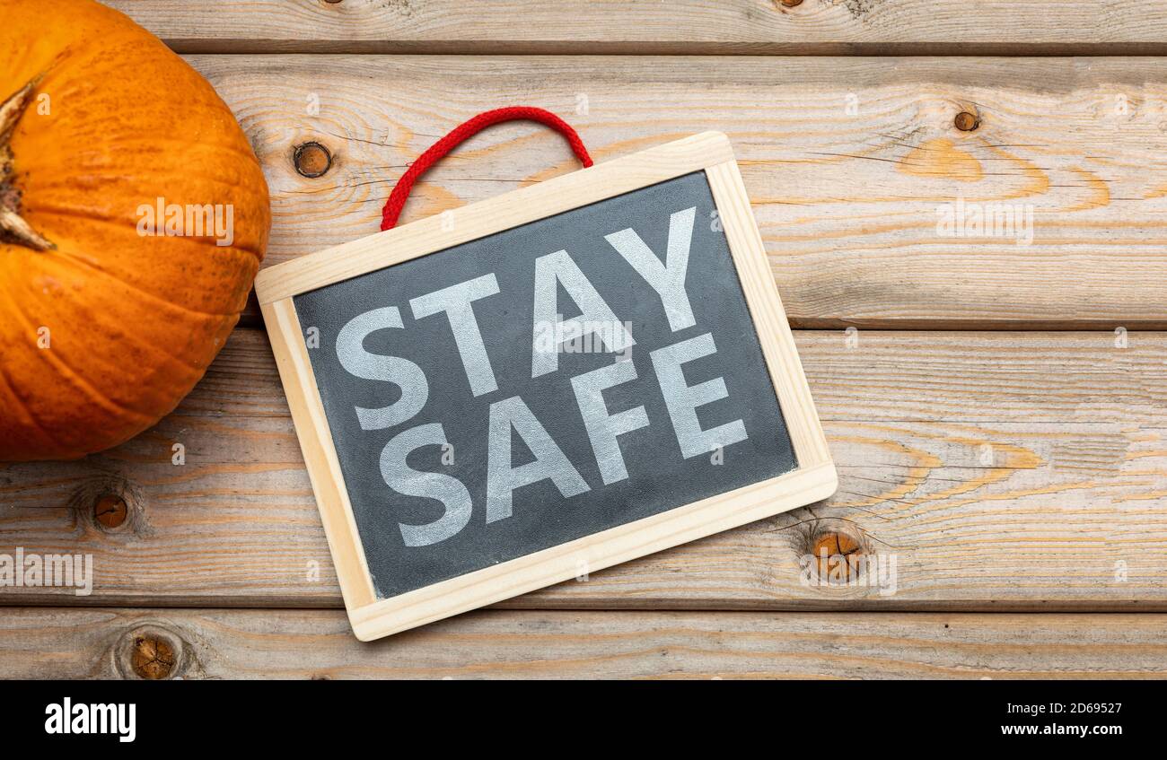 Thanksgiving COVID 19 days. STAY SAFE text message and pumpkin on wooden background. Coronavirus protection Stock Photo