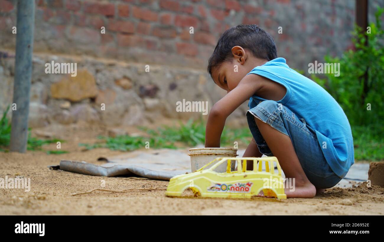 An Indian Village cute boy playing with his old car toy Stock Photo
