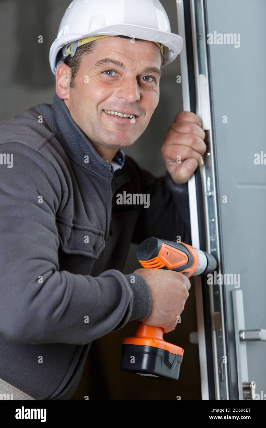 man drills a hole in a door Stock Photo Alamy