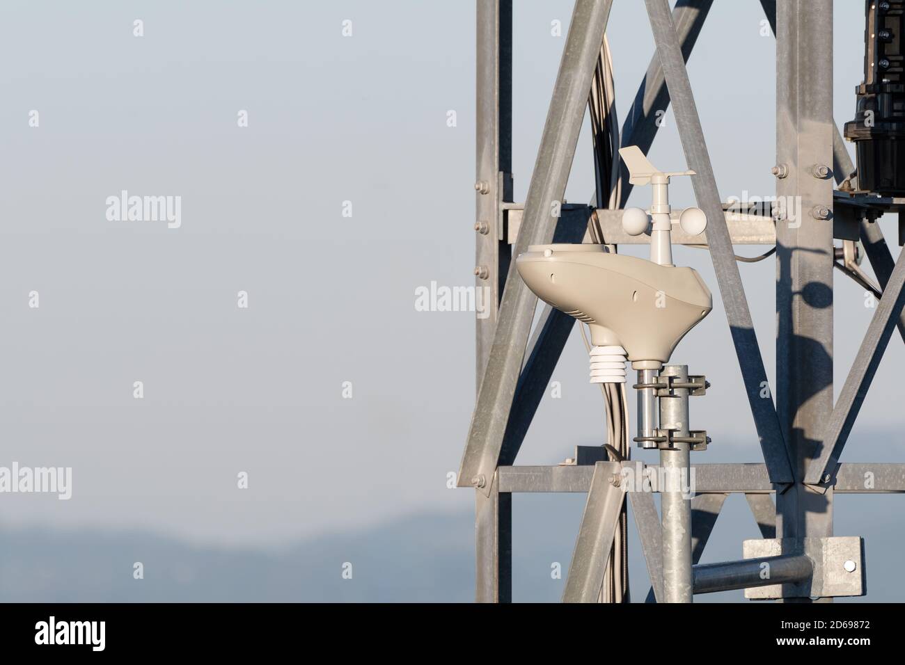 Close-up of rotating anemometer measuring wind speed mounted on steel tower. Wind measuring, weather and technology concepts Stock Photo