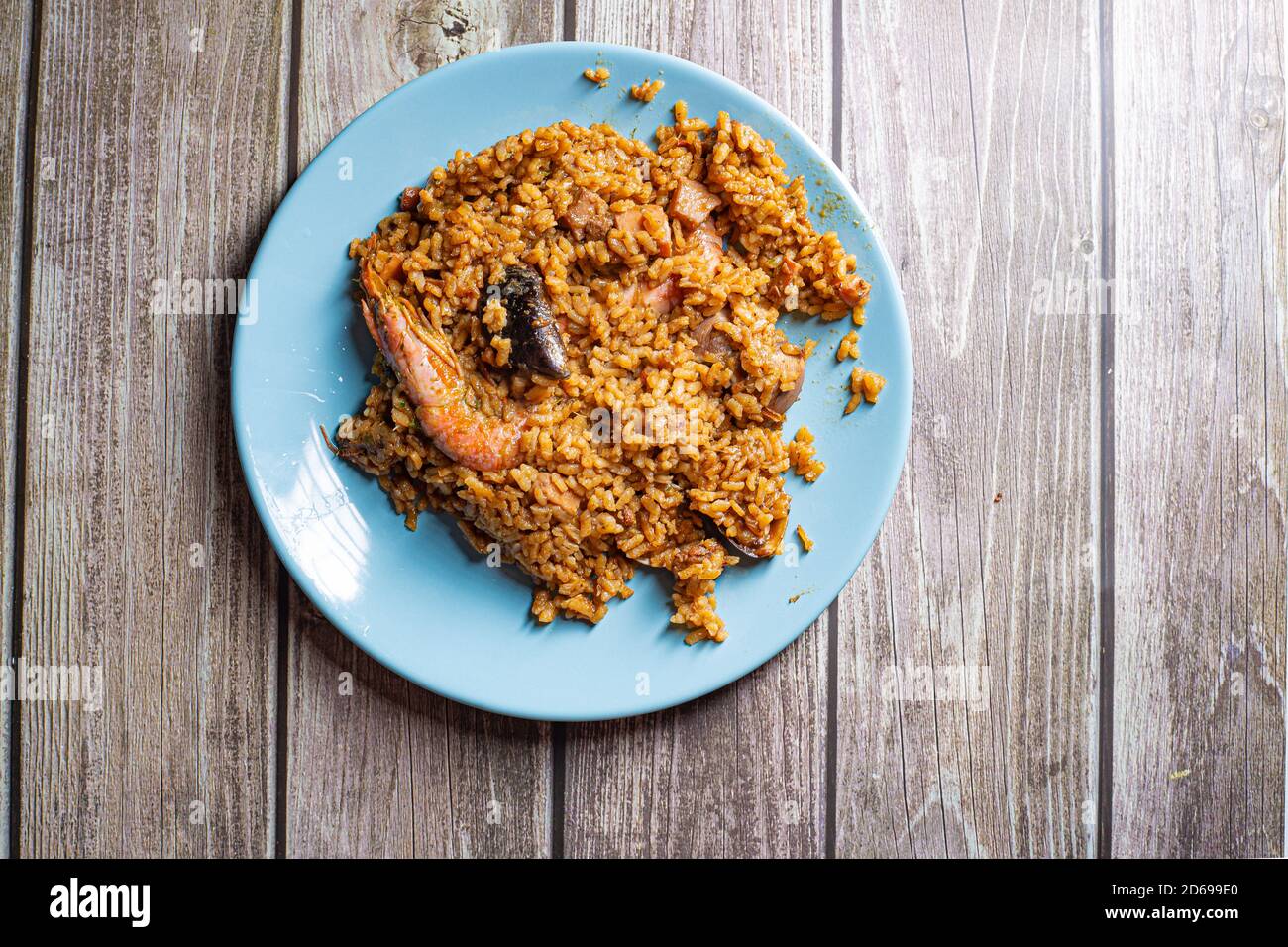 Paella yellow rice served with prawns and seafood on a blue plate Stock Photo