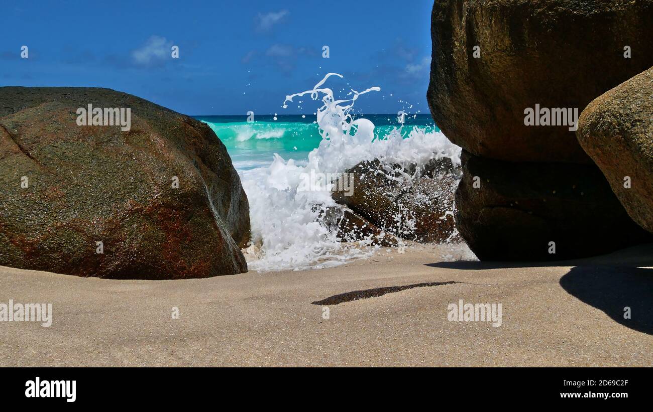 Closeup view of waves spilling over granite rocks with spray on beautiful tropical beach Anse Capucins, Mahe island, Seychelles. Stock Photo