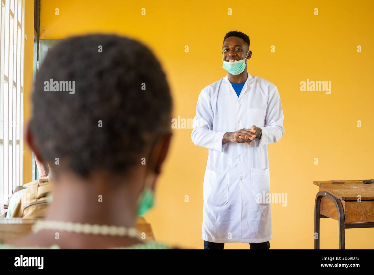 high school teacher in africa wearing a lab coat and face mask in class ...