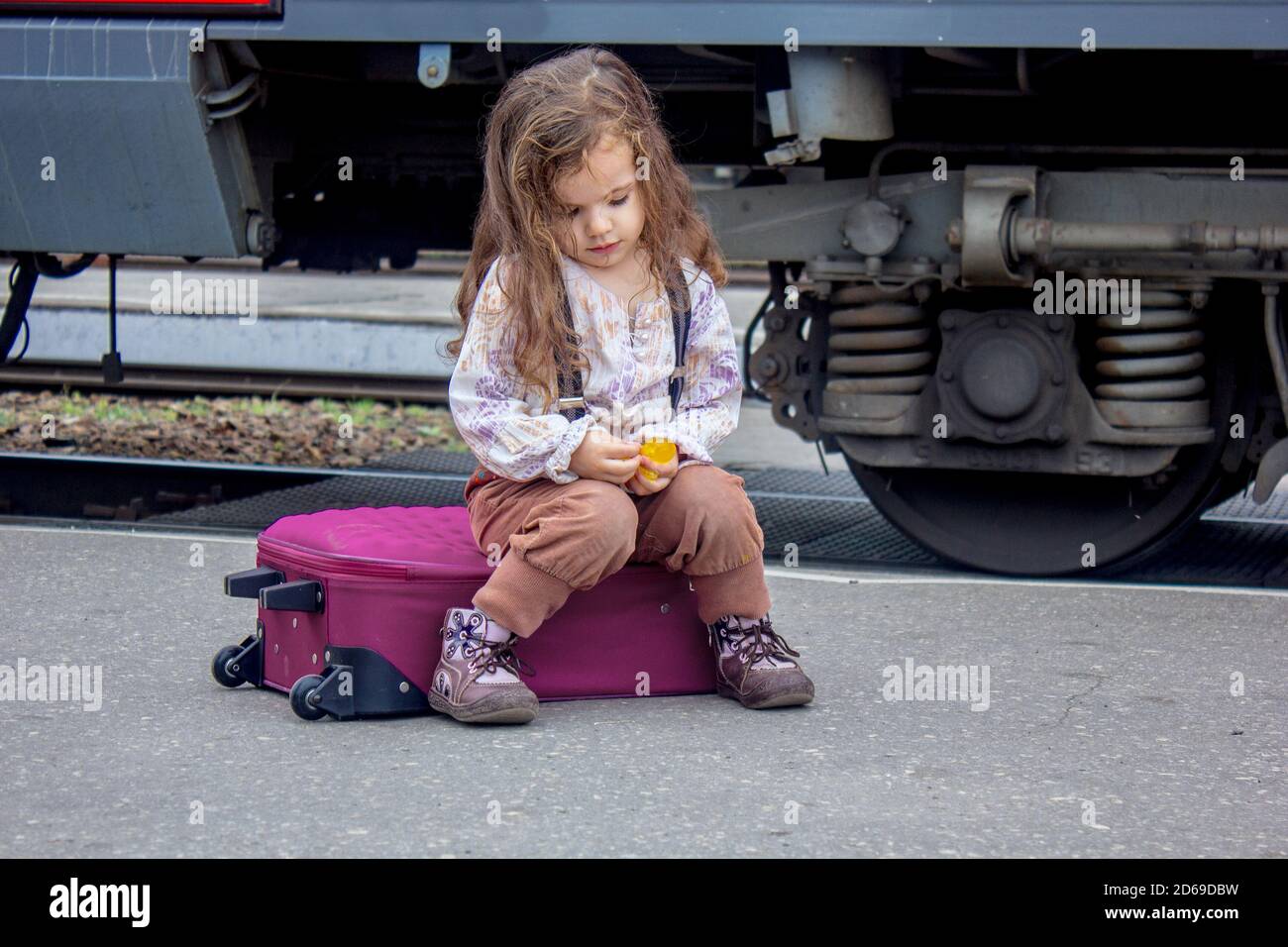 Little girl sitting at railway station with the train on background Stock Photo Alamy