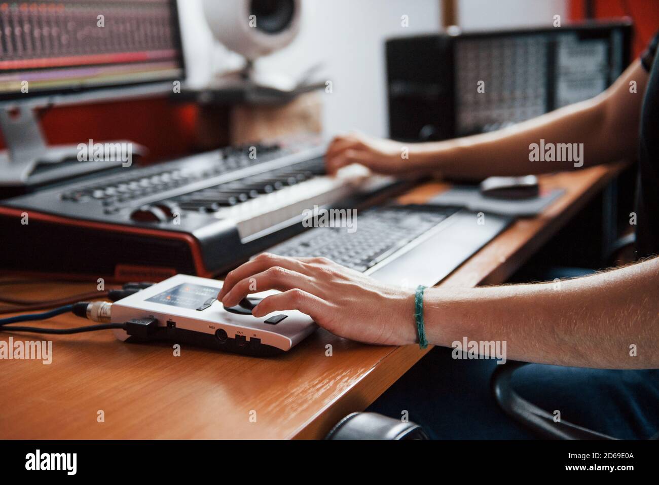 Playing midi keyboard. Sound engineer working and mixing music indoors
