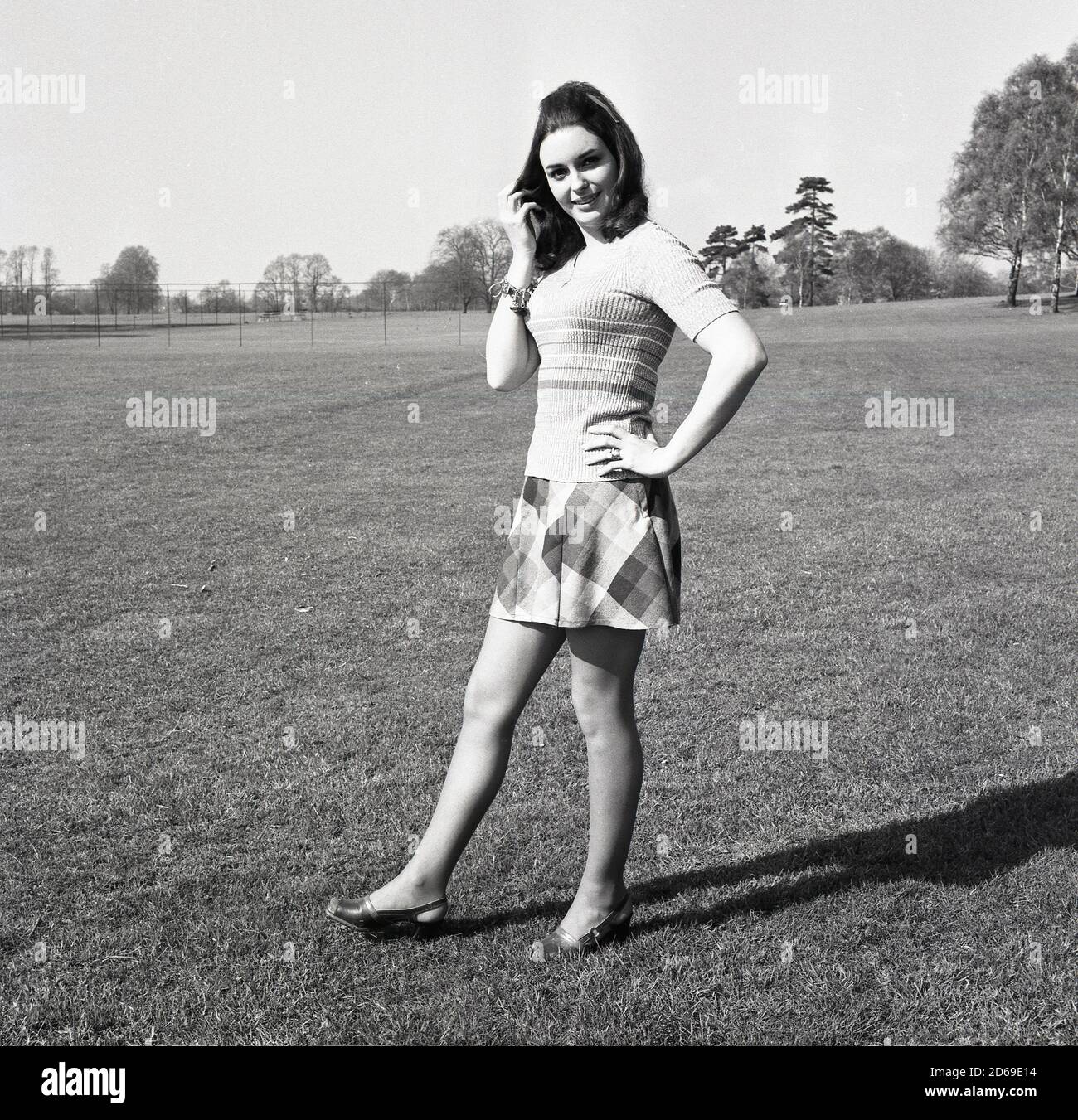 1971, historical, attractive young woman standing outside in the latest female fashions, short-sleeved cotton top and check-patterned skirt, London, England, UK. Stock Photo