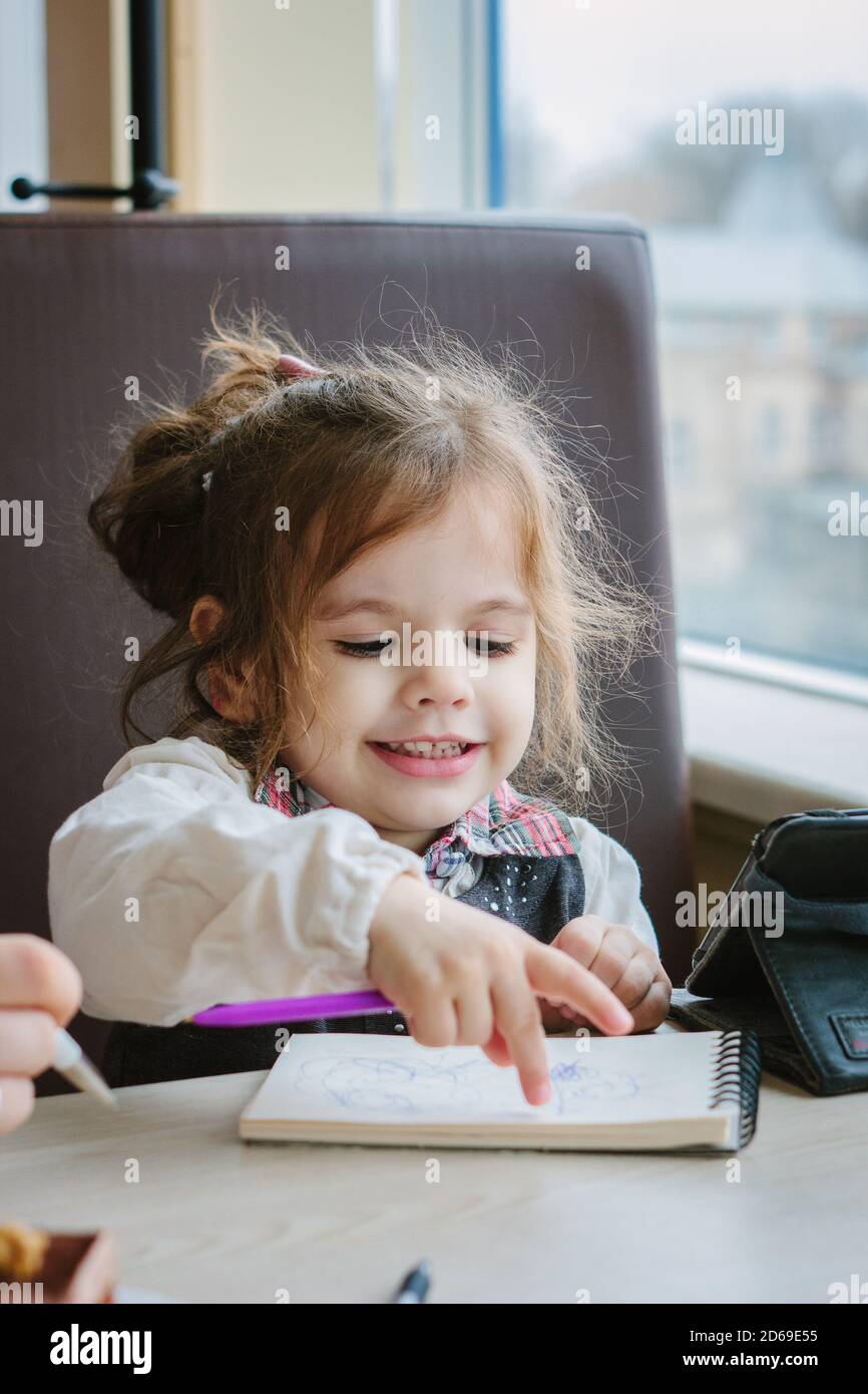 Little kid girl writing or drawing with pen in scetch book Stock Photo ...