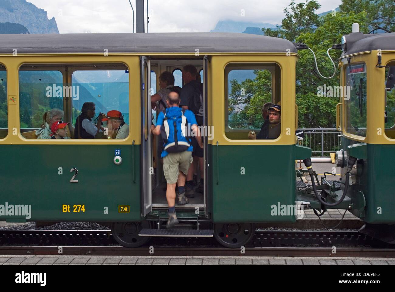 tourists getting on train in Wengen station Jungfrau region Oberland Switzerland Stock Photo
