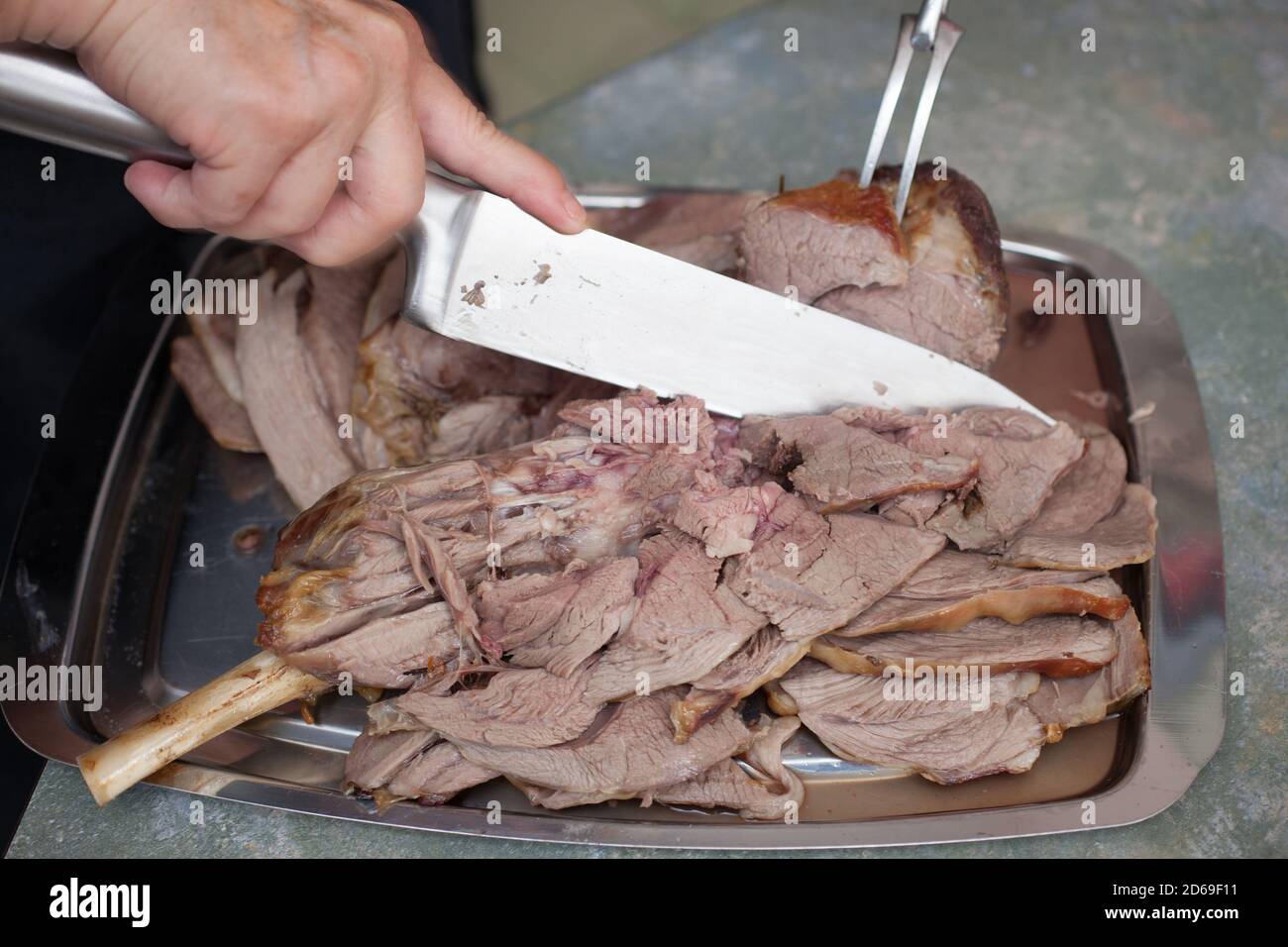 A joint of roast lamb being carved with a sharp knife Stock Photo Alamy