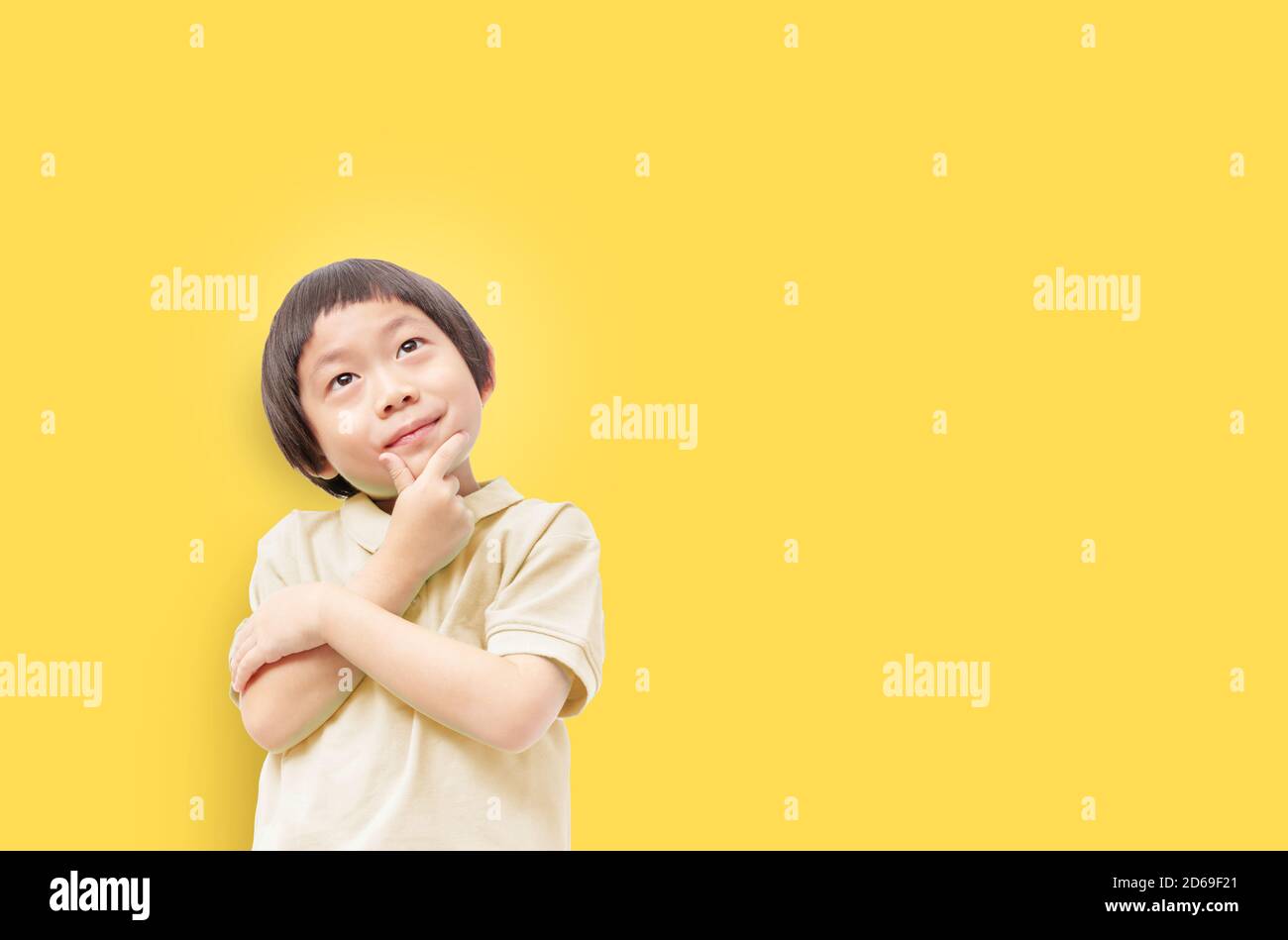 Think of the future of our children concept, Kid post arm on chin looking up with deep thinking on yellow background Stock Photo