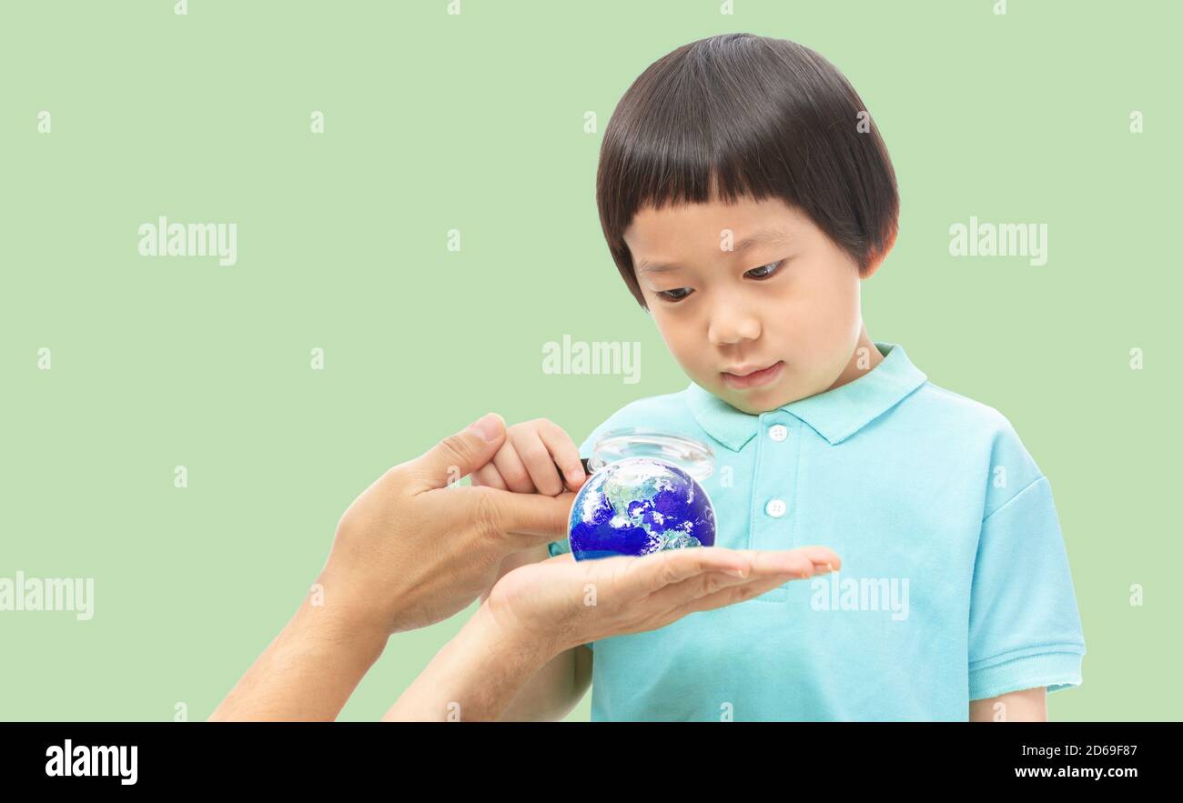 A boy looking through magnifying glass to the Earth on hands,  Teach Kids about the World Concept, Elements of this image furnished by NASA Stock Photo