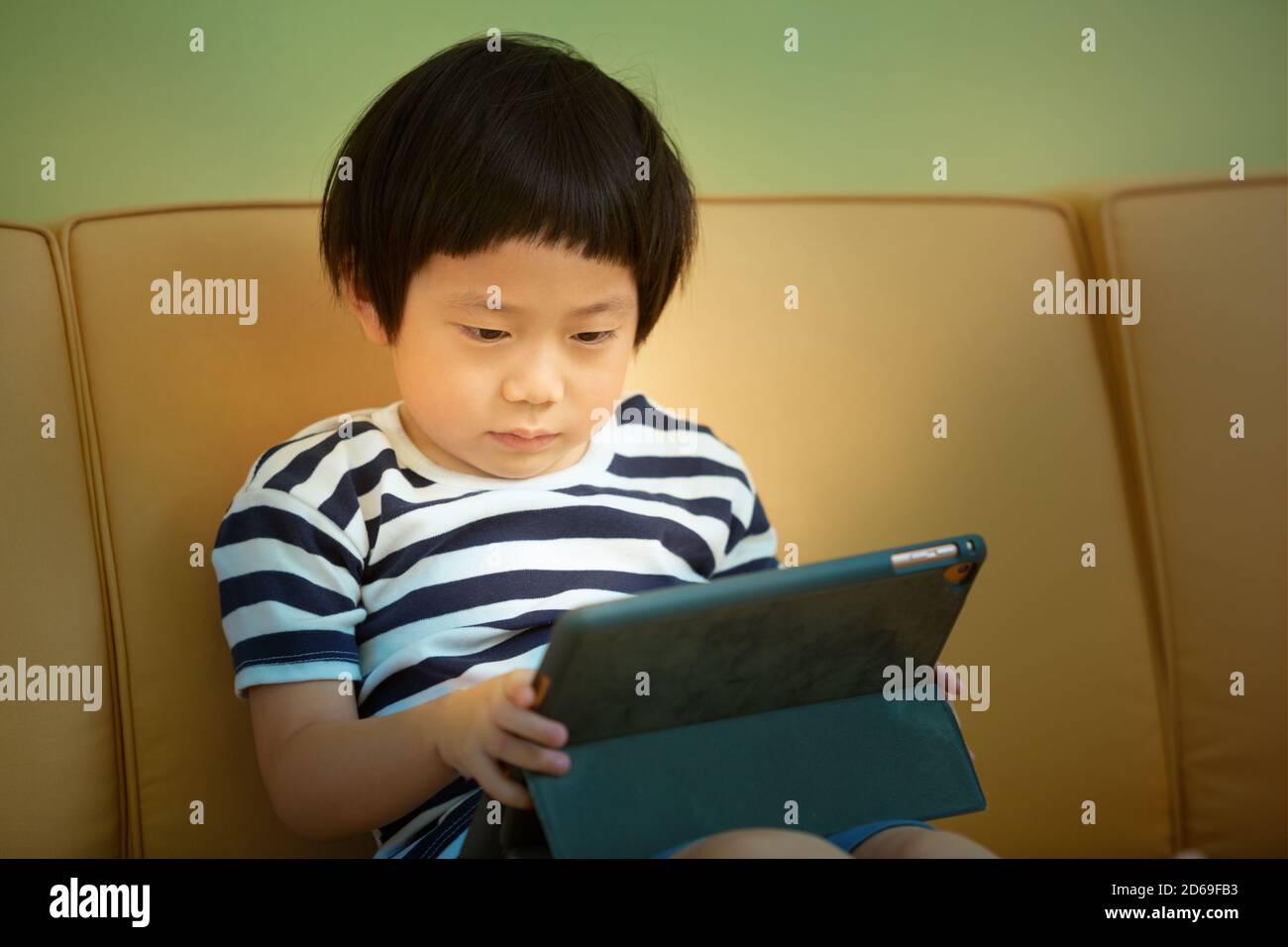 boy sitting on couch with Tablet computer, child spending too much time on computer concept Stock Photo