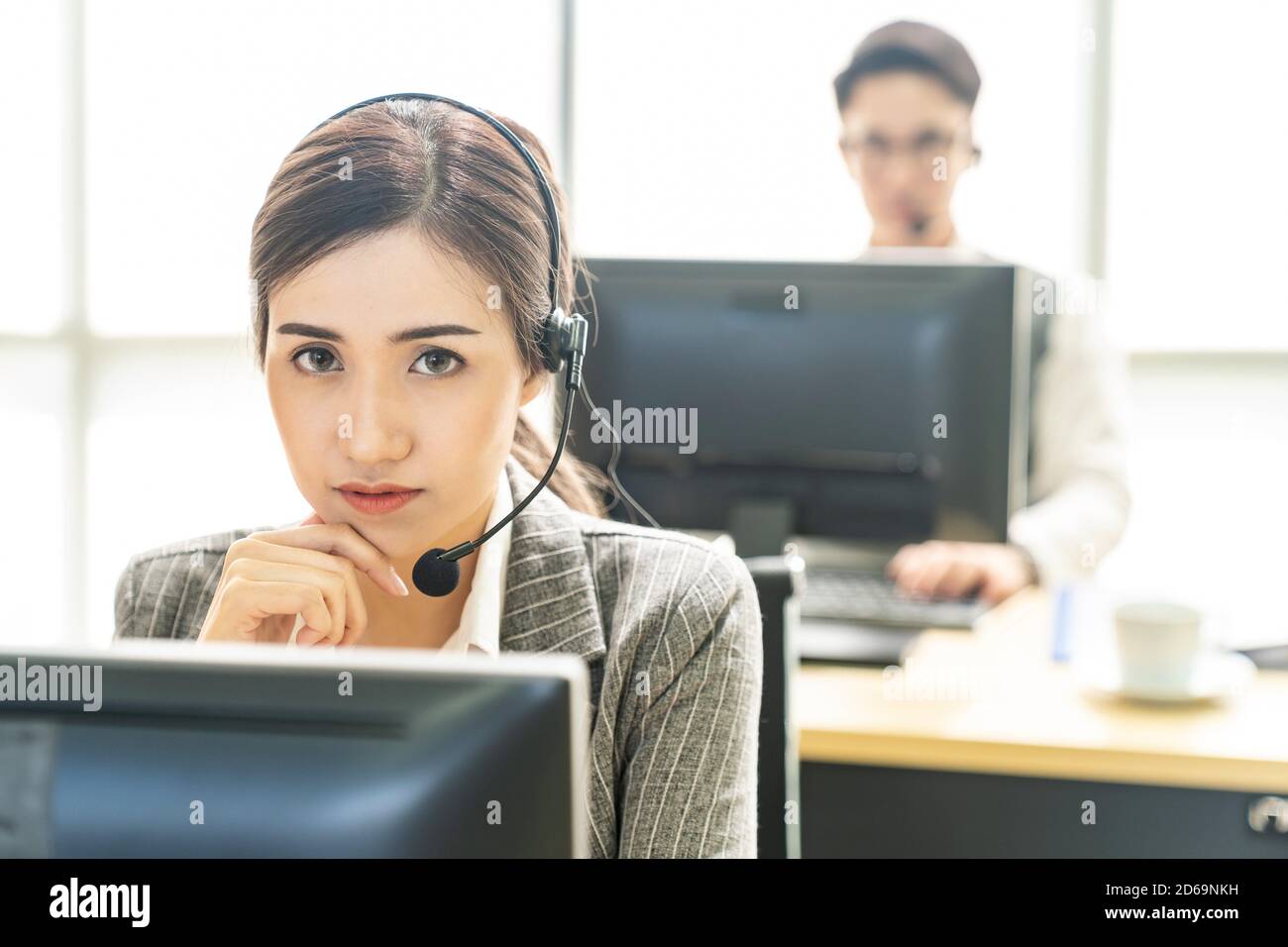 Portrait of Asian young adult friendly and confidence operator call centre with headsets in a call center as customer service and technical support. Stock Photo