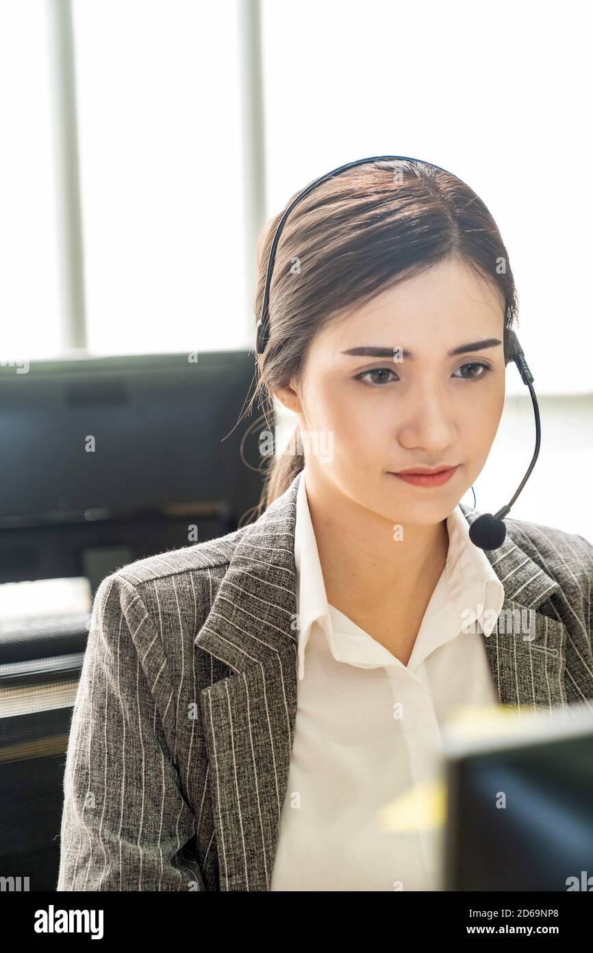 Portrait of Asian young adult friendly and confidence operator call centre with headsets in a call center as customer service and technical support. Stock Photo