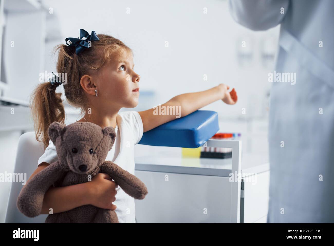 Preparation for blood sampling. Little girl with her toy in hands is in ...