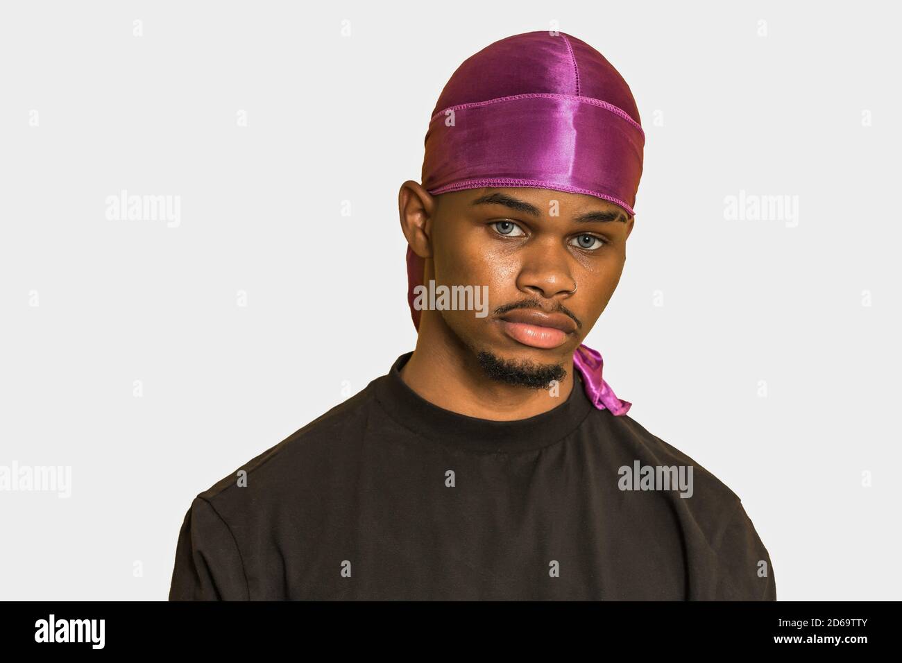 African American man in black t shirt and stylish headgear looking at camera against gray background. Stock Photo