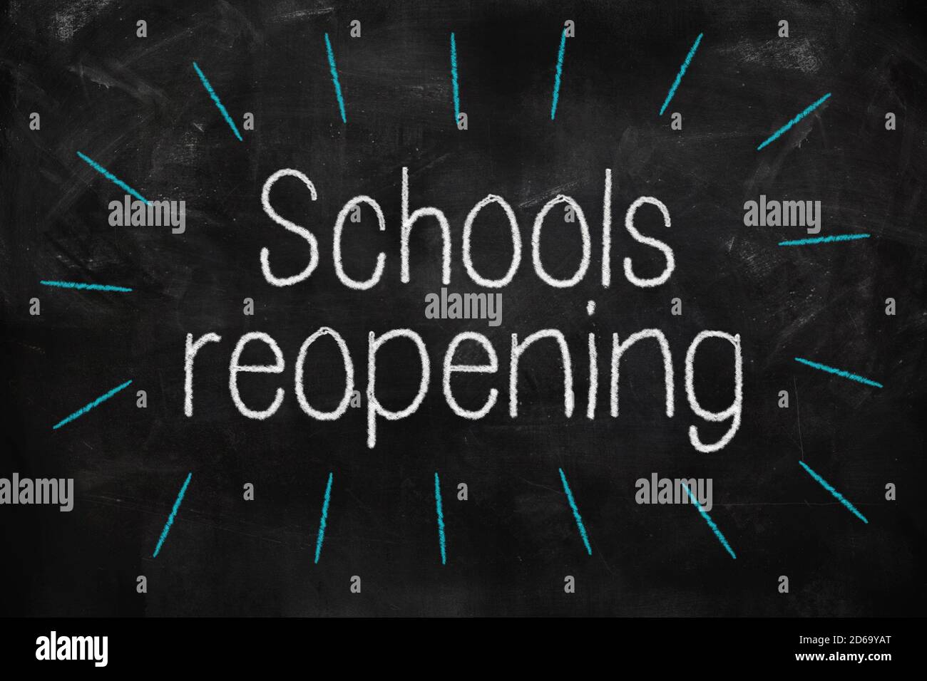 Schools reopening written with white and blue chalk on blackboard in classroom Stock Photo
