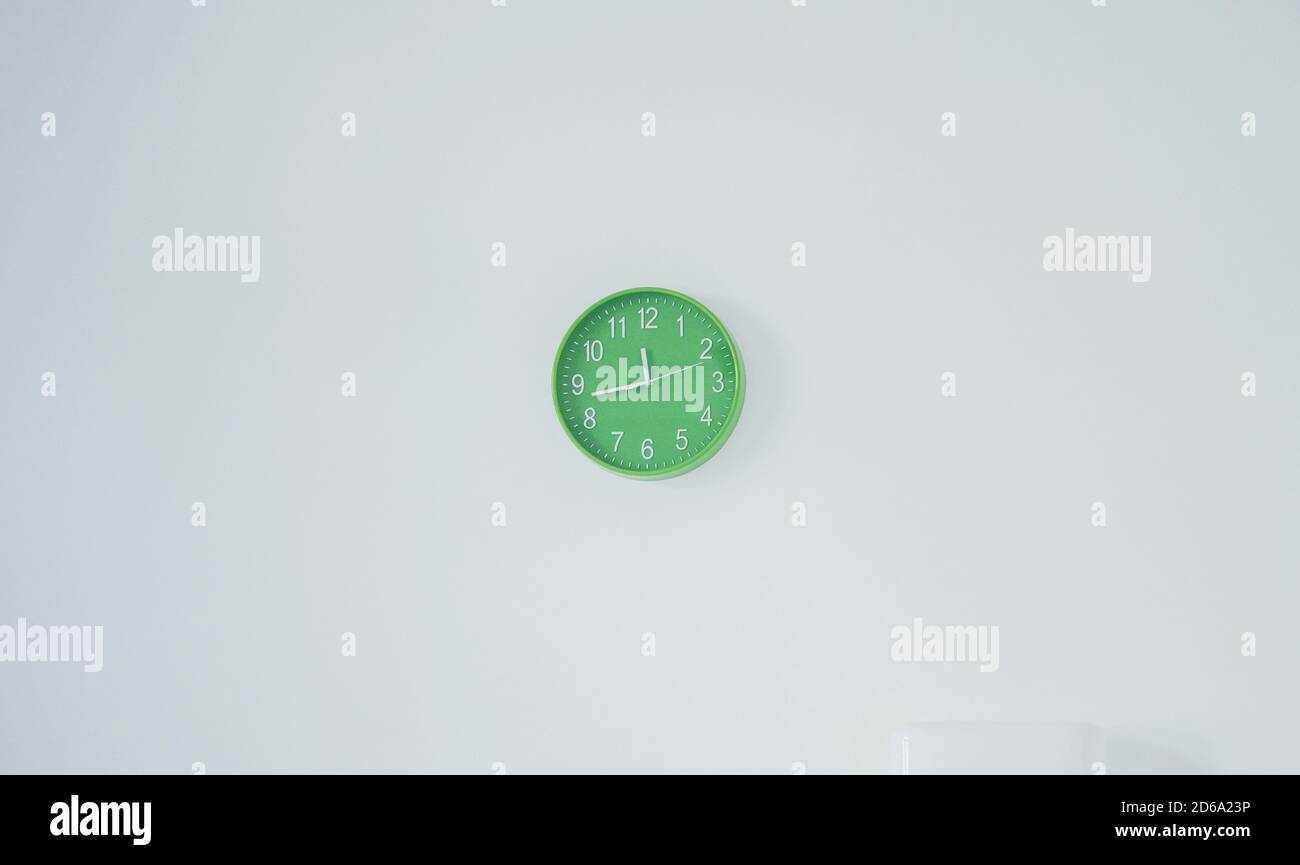 Minimalist photo of modern green clock that hanging on white wall Stock ...