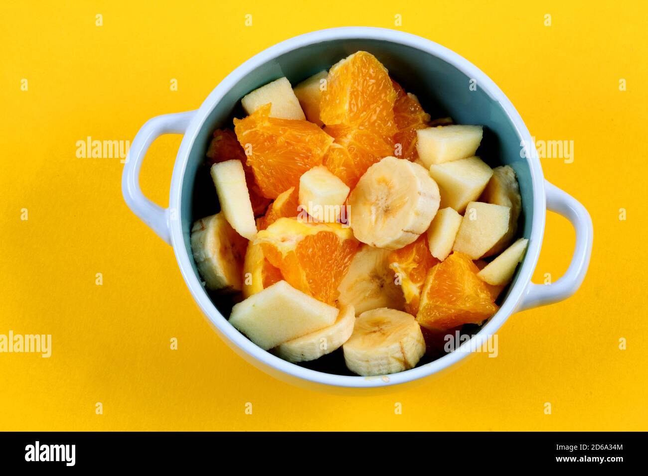 Fruit bowl with banana orange and apple on yellow background Stock